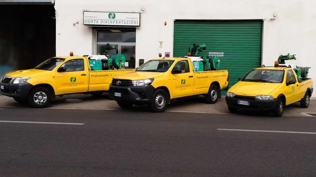 Tre pick-up gialli Costa Disinfestazioni con nebulizzatori verdi davanti alla sede con serranda verde e insegna